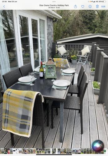 a wooden deck with a table and chairs on a patio at CRIB GOCH HOLIDAY CABIN SNOWDONIA in Caernarfon