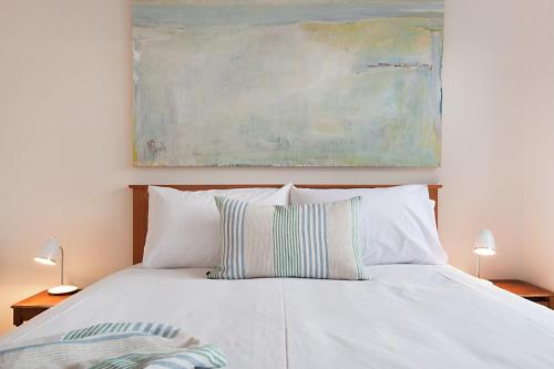 a white bed with two pillows and a painting at Salt Loft in Queenscliff