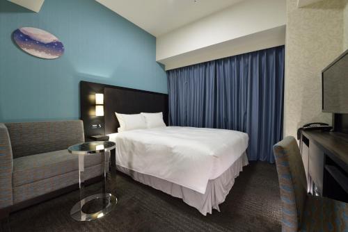 um quarto de hotel com uma cama e uma cadeira em The Royal Park Hotel Tokyo Haneda Airport Terminal 3 em Tóquio