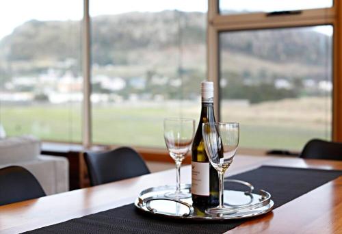 a bottle of wine and two glasses on a table at Stanley Beach House with Stunning Nut Views! in Stanley