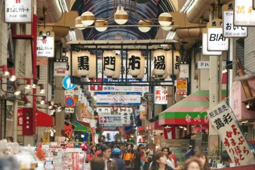 a street with a crowd of people walking through a market at Ash Court Joto in Osaka