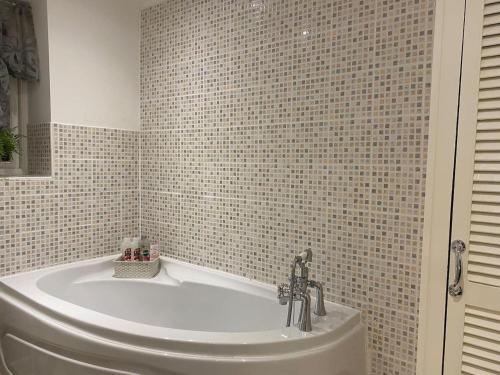 a bath tub in a bathroom with a tiled wall at Beautiful 1 Bed Apartment in the Heart of Ludlow in Ludlow