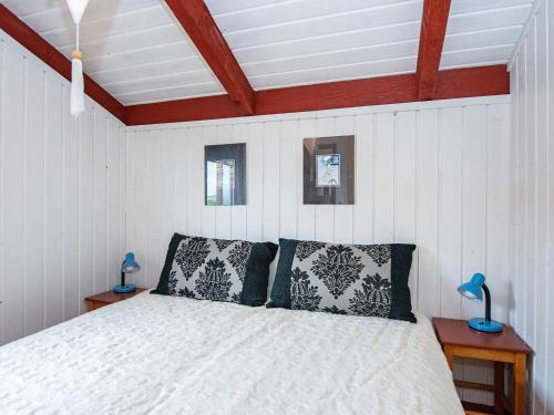 een slaapkamer met een wit bed met 2 kussens bij Holiday home Hvide Sande CXI in Bjerregård