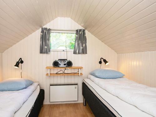 Duas camas num pequeno quarto com uma janela em Holiday home Skjern XV em Skjern