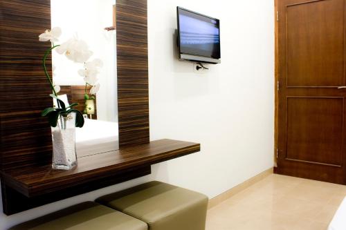 Cette chambre dispose d'une télévision et d'un vase avec des fleurs. dans l'établissement Grand Marto Hotel, à Yogyakarta