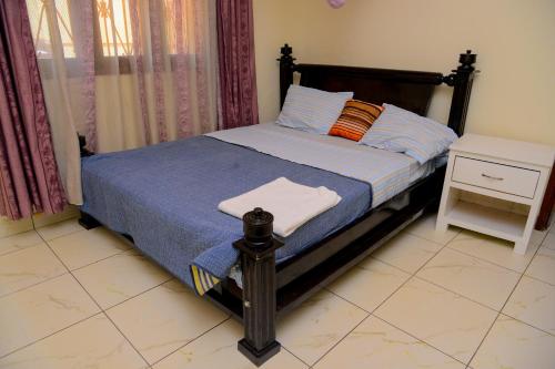 MODERN LUXURIOUS 2BEDS HOUSE IN KAMPALA CITY CTR في كامبالا: غرفة نوم مع سرير مع لحاف أزرق