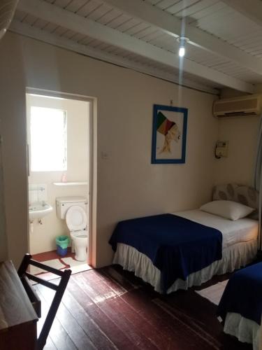 a bedroom with a bed and a toilet and a window at Rio Guesthouses in Christ Church