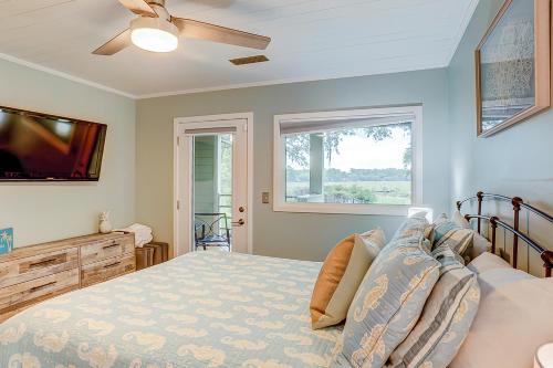 a bedroom with a bed with a ceiling fan and a window at Seabrook Sanctuary - 1706 Courtside in Seabrook Island