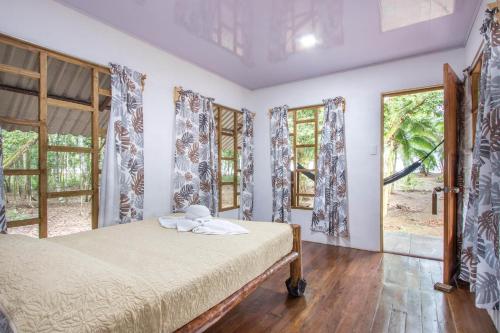 a bedroom with a bed in a room with windows at Playa Ganadito Ecolodge in Drake
