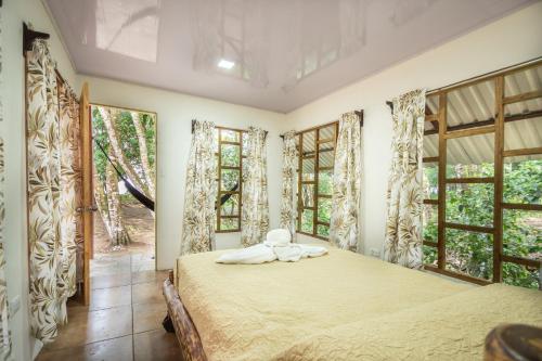 ein Schlafzimmer mit einem Bett in einem Zimmer mit Fenstern in der Unterkunft Playa Ganadito Ecolodge in Drake