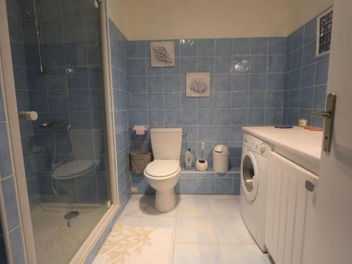 La salle de bains est pourvue de carrelage bleu, de toilettes et d'une douche. dans l'établissement Studio à Bénodet à 100m de la plage, balcon, thalasso et restaurants à proximité - FR-1-481-120, à Bénodet