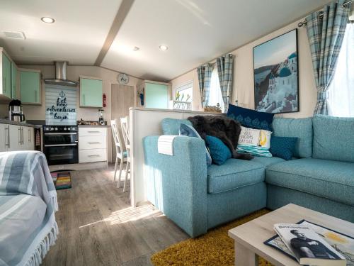 a living room with a blue couch and a table at Chalet in Oostkapelle near the Beach in Oostkapelle