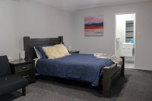 a bedroom with a bed with a blue comforter and a chair at City Centre Escape in Napier