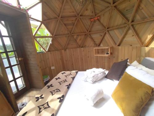 Cama grande en habitación con techo de madera en Paraíso Glamping La Vega, en La Vega