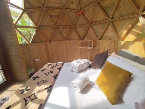 Cama grande en habitación con techo de madera en Paraíso Glamping La Vega, en La Vega