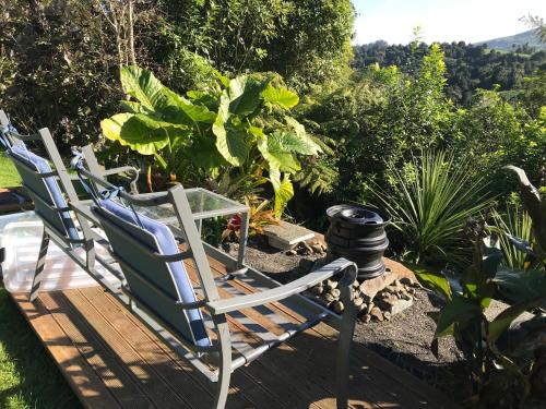 two chairs and a table on a deck with plants at The Dome Waikino in Waikino