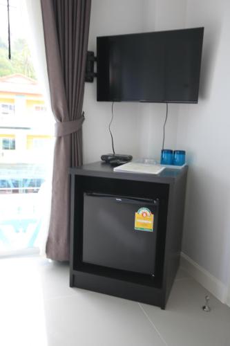 a room with a tv on a wall with a table at Karon Sea Side in Karon Beach