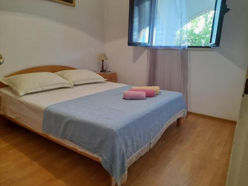 a bedroom with a bed with two pink pillows on it at Apartments Jere - with parking in Sutivan