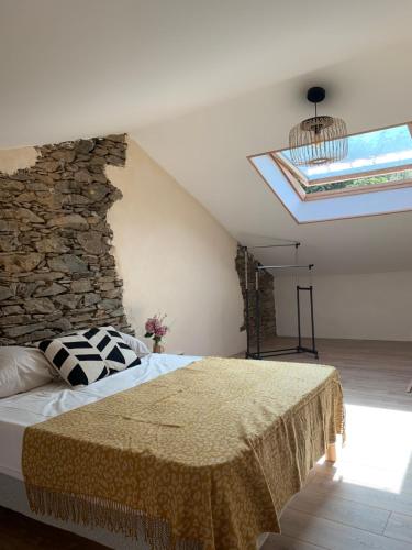 une chambre avec un lit et un mur en pierre dans l'établissement Très jolie maison aux portes du Cap Corse, à Sisco