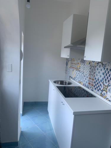 una cocina con armarios blancos y azulejos en la pared en Maison emi, en Montecorice