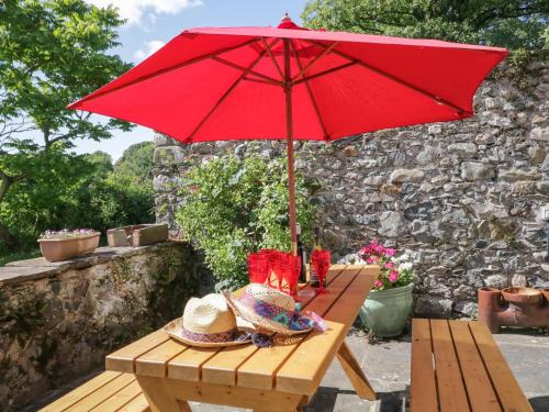 a picnic table with a red umbrella on a patio at Beckside Farm in Millom