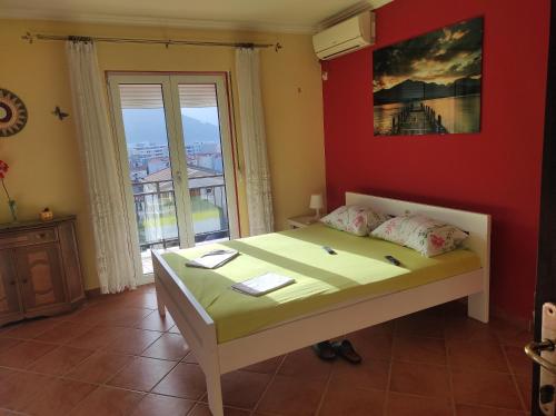 a bedroom with a bed with a red wall and a window at Guesthouse Djacic in Budva