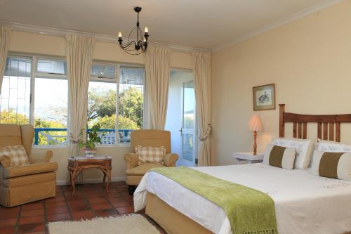 a bedroom with a large bed and chairs and windows at Yellowwood Lodge in Knysna