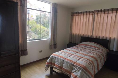 sypialnia z łóżkiem i dużym oknem w obiekcie Departamento 3 niveles- Vista Panoramica 360 grados a toda la ciudad y Lago Titicaca w mieście Puno