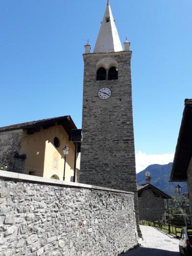 a tall tower with a clock on a building at The Green Owl in Antey-Saint-André