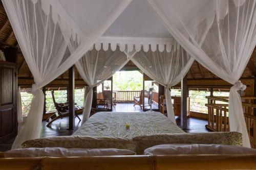 a bedroom with a canopy bed in a house at Bali Firefly BnB in Ubud