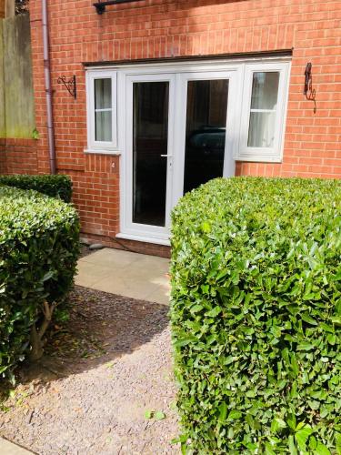 uma porta da frente de uma casa de tijolos com arbustos em 1 Bedroom Apartment - Bedworth Nuneaton Coventry em Attleborough