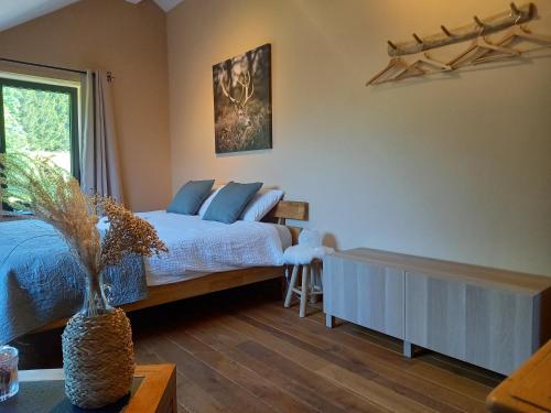 a bedroom with a bed with blue pillows and a window at Le Clos du Cerf - Silence & nature in Stoumont