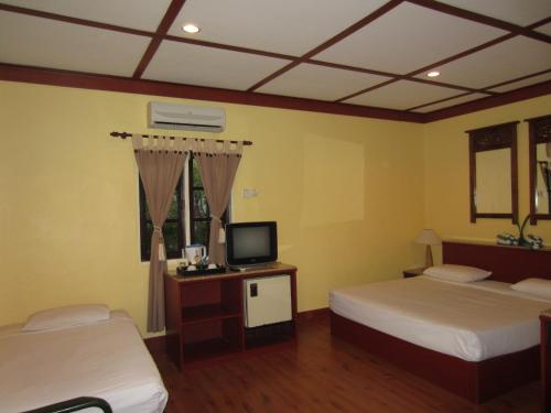 a hotel room with two beds and a television at Sunset Beach Resort in Pantai Cenang