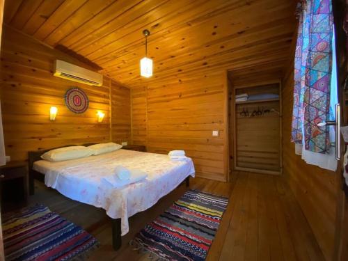 a bedroom with a bed in a wooden cabin at Tiny House Ceviz Kayaköy Jungle Camping in Fethiye