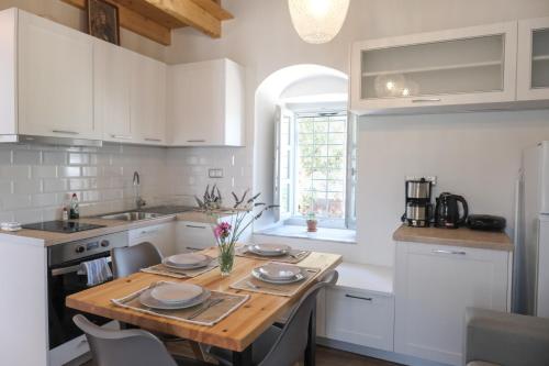 a kitchen with white cabinets and a wooden table at Metochi Athentic Hospitality in Hydra