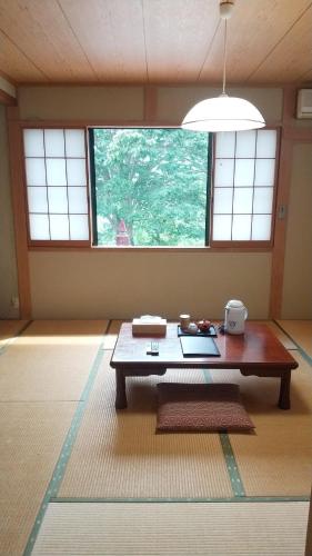 a living room with a table and a window at Hataya Onsen Sasa no yu in Katashina