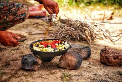 una persona está preparando un tazón de comida en el suelo en Dana Gate Lodge en Ḑānā