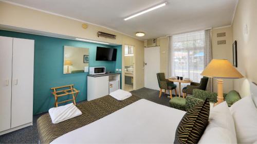 a hotel room with a bed and a living room at Silver Oaks Motel in Gilgandra