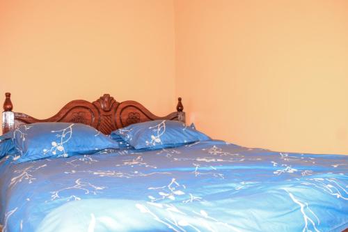 uma cama com lençóis azuis e almofadas azuis em JC ITEN Guest House em Iten