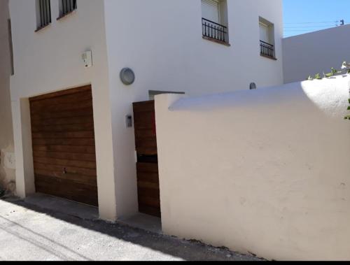 a white wall next to a garage with a wooden door at Rêveries maritimes in Marseille