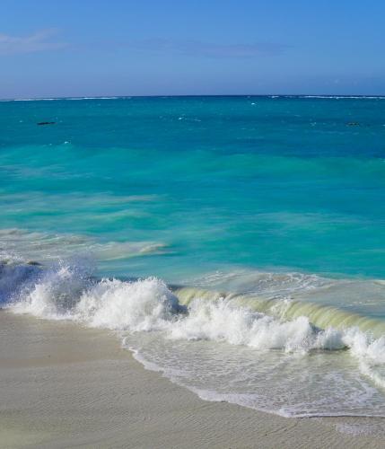 a wave in the ocean on a sandy beach at Safira Blu Luxury Resort & Villas in Nungwi