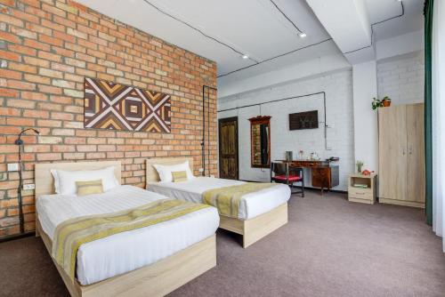 a bedroom with two beds and a brick wall at Olive Ala-Archa Hotel & SPA in Verkhnyaya Alaarcha
