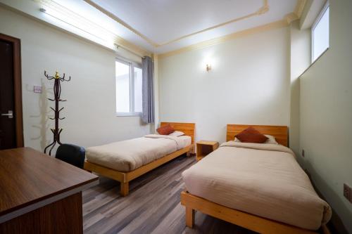 a room with two beds and a table and a desk at Shine Homestay Famille Francophone - Shine Home and Apartment in Kathmandu
