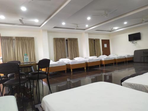 a room with white beds and chairs and a flat screen tv at BAY INN in Chennai