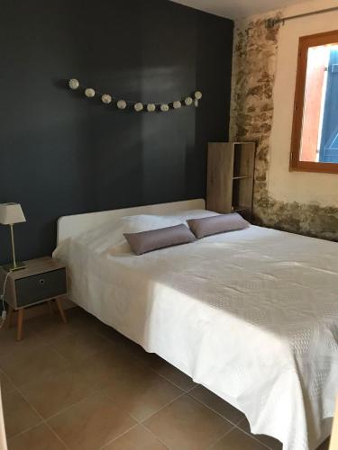 - une chambre avec un lit blanc et un mur noir dans l'établissement O’gîtes des colombes, à Colombiers