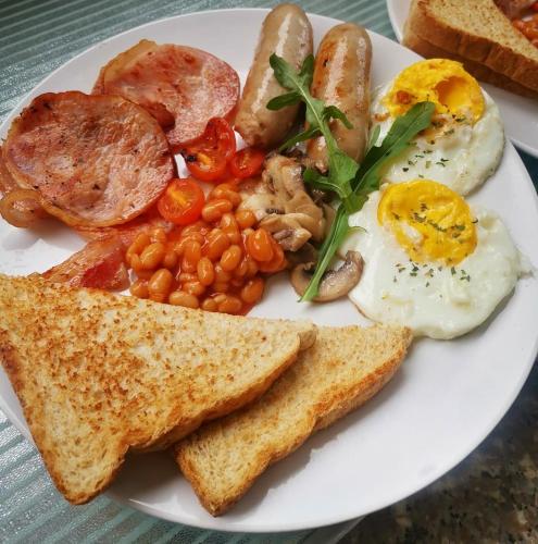 a plate of breakfast food with eggs beans and toast at Santorini Guesthouse in Amanzimtoti