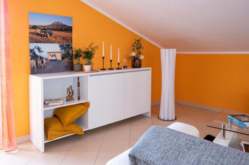 a living room with orange walls and a white cabinet at Andrea's House in Locri