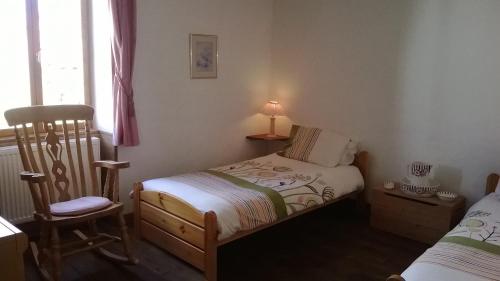 Un dormitorio pequeño con dos camas y una silla. en La Châtaigne Dorée, en Saint-Pierre-de-Fursac