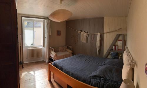 1 dormitorio con 1 cama con edredón azul y ventana en Charmante maison de ville dans un bourg typique en Noyal-Muzillac