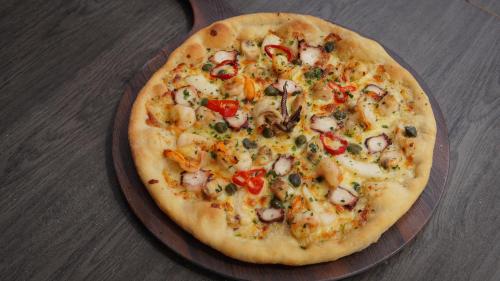 a pizza on a wooden plate on a table at Safira Blu Luxury Resort & Villas in Nungwi